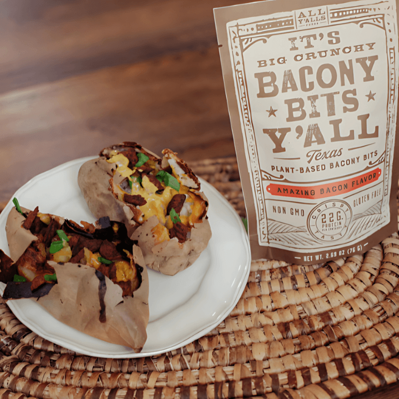 A delicious duo of baked potatoes topped with creamy vegan cheese and All Y’all’s Foods' Bacony Bits Y’all, the perfect non-GMO, gluten-free topper; shop now at https://allyallsfoods.com/.
