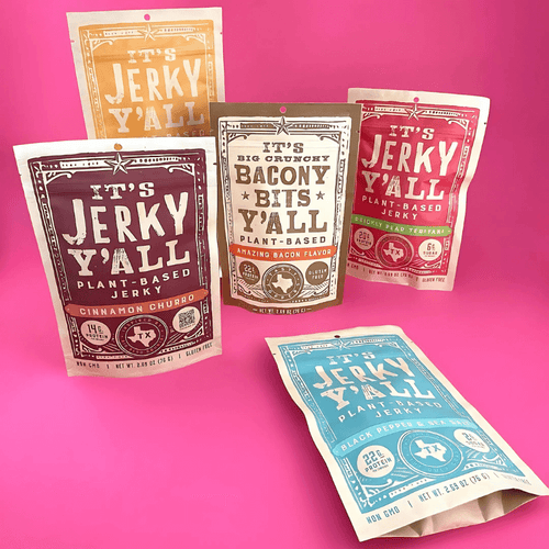 A vibrant display of It’s Jerky Y’all plant-based jerky packs in various flavors set against a bold pink background, highlighting the product lineup.