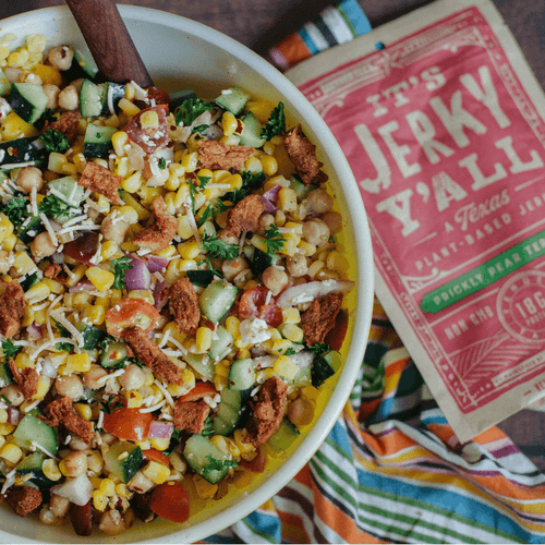 A vibrant bowl of fresh chickpea salad topped with All Y’alls Foods' Prickly Pear Teriyaki vegan jerky, adding a smoky-sweet crunch; shop now at https://allyallsfoods.com/.