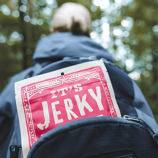 Backpack with a pack of It’s Jerky Y’all vegan jerky, ideal for on-the-go plant-based snacking during outdoor adventures.