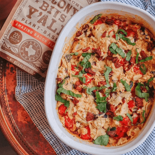 A flavorful vegan casserole dish topped with fresh herbs and plant-based bacon bits from All Y'alls Foods, perfect for vegan snacks recipes, displayed next to a package of their Bacon Bits Y'all.