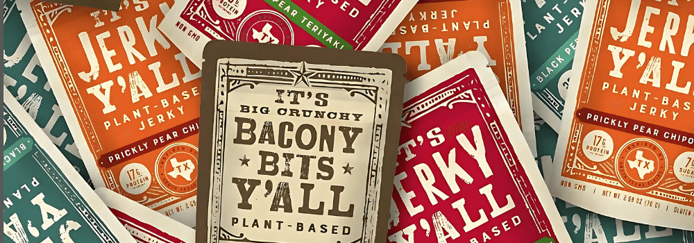 An assortment of colorful, plant-based jerky and bacony bits packaging from It's Jerky Y'all, showcasing various flavors packed with plant-based proteins.