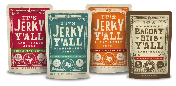 An assortment of All Y'all's Foods plant-based products, including Prickly Pear Teriyaki and Black Pepper & Sea Salt jerky flavors alongside crunchy bacon-flavored bacon bits.